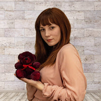 A woman holds a maroon bear that is 6 inches tall while sitting