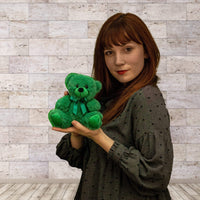 A woman holds a green bear that is 6 inches tall while sitting