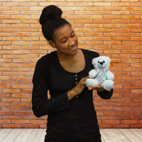 A woman holds a light blue bear that is 6 inches tall while sitting