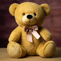 A beige bear that is 14 inches tall while sitting wearing a matching bow