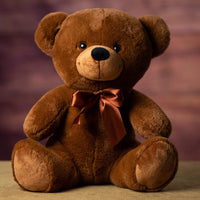 A brown bear that is 14 inches tall while sitting wearing a matching bow