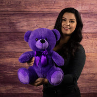 A woman holds a purple bear that's 14 inches tall while sitting