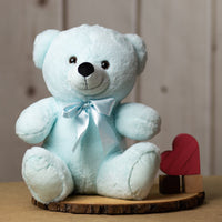 A light blue bear that is 14 inches tall while sitting wearing a matching bow next to wooden blocks