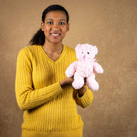 A woman holds a light pink bear that's 10 inches tall while standing 