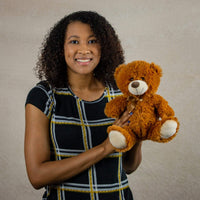 A woman holds a brown bear that is 10 inches tall while sitting