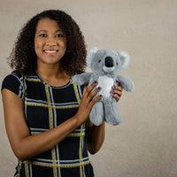 A woman holds a grey koala that is 11 inches tall while standing