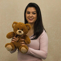 A woman holds a brown bear that is 10.5 inches tall while sitting