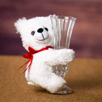 A white bear that is 5.5 inches tall while sitting hugging a vase