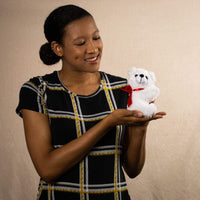 A woman holds a white bear that is 5.5 inches tall while sitting