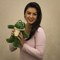 A woman holds a green alligator that is 11 inches tall while standing