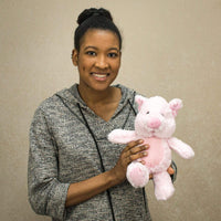 A woman holds a pink pig that is 11 inches tall while standing
