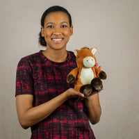 A woman holds a brown horse that is 11 inches tall while standing