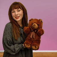 A woman holds a brown bear that is 14 inches tall while standing