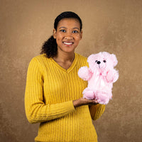 A woman holds a pink bear that is 12 inches tall while standing