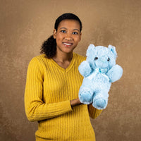 A woman holds a  blue bear that is 14 inches tall while standing