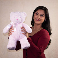A woman holds a pink bear that is 15 inches tall while standing with "My First Bear" on its left paw