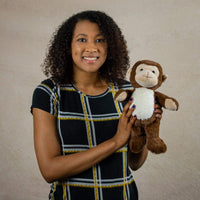 A woman holds a brown monkey that is 13 inches tall while standing with a white belly