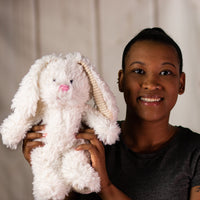 A woman holding a white scruffy rabbit that is 13 inches tall while standing with corduroy ears and feet