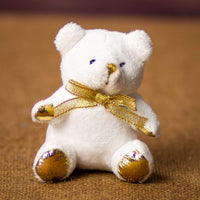 A white bear that is 3.5 inches tall while sitting with a gold bow and paws