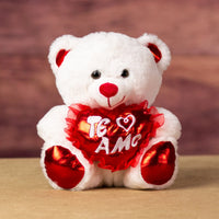 A white bear that is 10 inches tall while sitting with red feet and ears holding a shiny red "Te Amo" heart