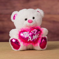 A white bear that is 10 inches tall while sitting with pink feet and ears holding a shiny pink "Te Amo" heart