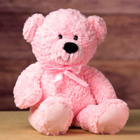 A pink bear that is 22 inches tall while standing wearing a matching bow