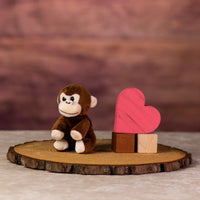 A brown monkey that is 5 inches tall while sitting next to wooden blocks