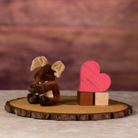 A brown moose that is 5 inches tall while sitting on top of a piece of wood