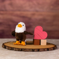 A eagle that is 5 inches tall while standing next to wooden blocks