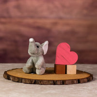 A gray elephant that is 5 inches tall while sitting next to wooden blocks