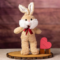 A beige rabbit that is 13 inches while standing wearing a red bow next to wooden blocks