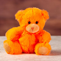 stuffed 6 in orange bright and cheery bear with bow around her neck