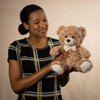 A woman holds a beige bear that is 11 inches tall while sitting