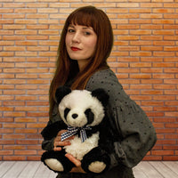 A woman holds a black and white panda that is 11 inches tall while sitting