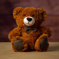 A brown bear that is 10 inches tall while sitting wearing a bowtie that matches his ears and paw prints