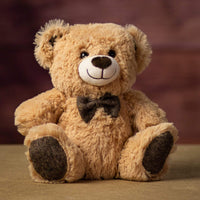 A beige bear that is 10 inches tall while sitting wearing a bowtie that matches his ears and paw prints