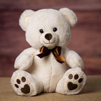 A cream bear that is 11 inches tall while sitting with paw prints on its feet
