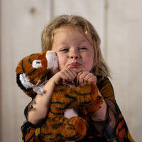 A little girl holding a stripped tiger that is 10 inches tall while sitting