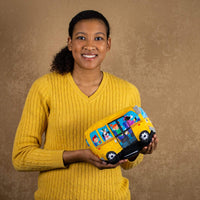 A woman holds a yellow animated/singing school bus that is 8 inches from front to back