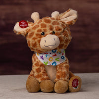 A spotted sitting giraffe that is 10 inches tall while sitting wearing a ABCs and 123s covered bandanna 