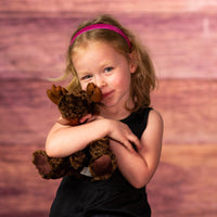 girl holding 7 in stuffed little brown moose with bow 