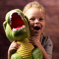 A girl holding a green dinosaur that is 14 inches tall while standing