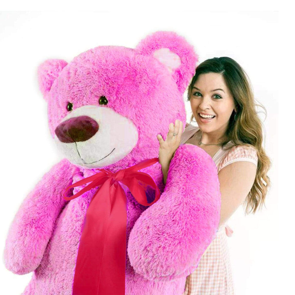 A woman holds a hot pink bear that is 60 inches tall while standing
