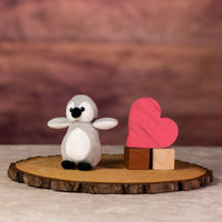 A black and gray penguin that is 5 inches tall while standing next to wooden blocks