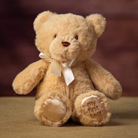 A sitting beige bear that is 10 inches tall while standing with "My First Bear" on its left paw