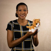 A woman holds a orange tabby cat that is 7 inches tall while sitting