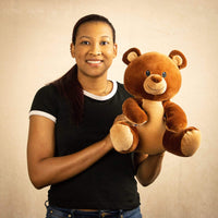 A woman holds a brown bear that is 12 inches tall while sitting