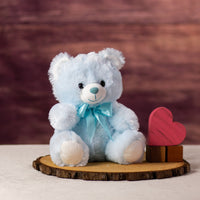 A blue bear that is 10 inches tall while sitting next to wooden blocks