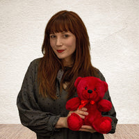 A woman holds a red bear that is 9 inches tall while sitting