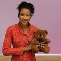 A woman holds a brown bear that is 9 inches tall while sitting